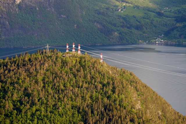 View to the fjord (Storfjorden) with huge electric pylons on the top of a hill, Sjøholt, Norway